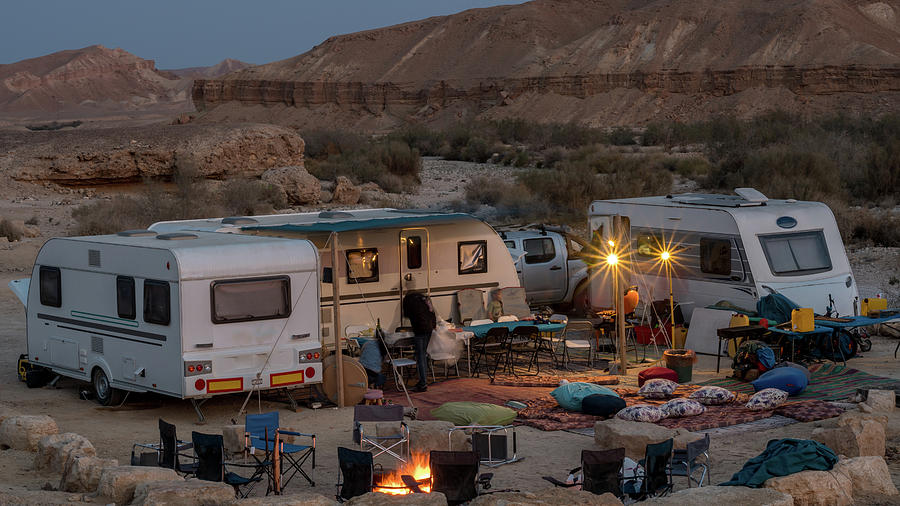 The meme shows a campsite in a desert with a camper and a car, but the camper is on fire and the people inside are frantically waving for help. The text on the meme reads "When you finally get the campsite to be in the middle of nowhere and it's on fire".